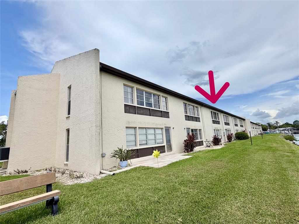 An exterior view of a two-story apartment building with a pink arrow pointing upward — 4533 MARINE PARKWAY UNIT 204, NEW PORT RICHEY, FL