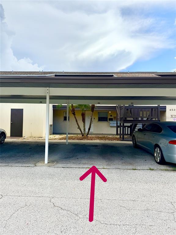 A covered parking area with a palm tree in front of a multi-unit building — 4533 MARINE PARKWAY UNIT 204, NEW PORT RICHEY, FL