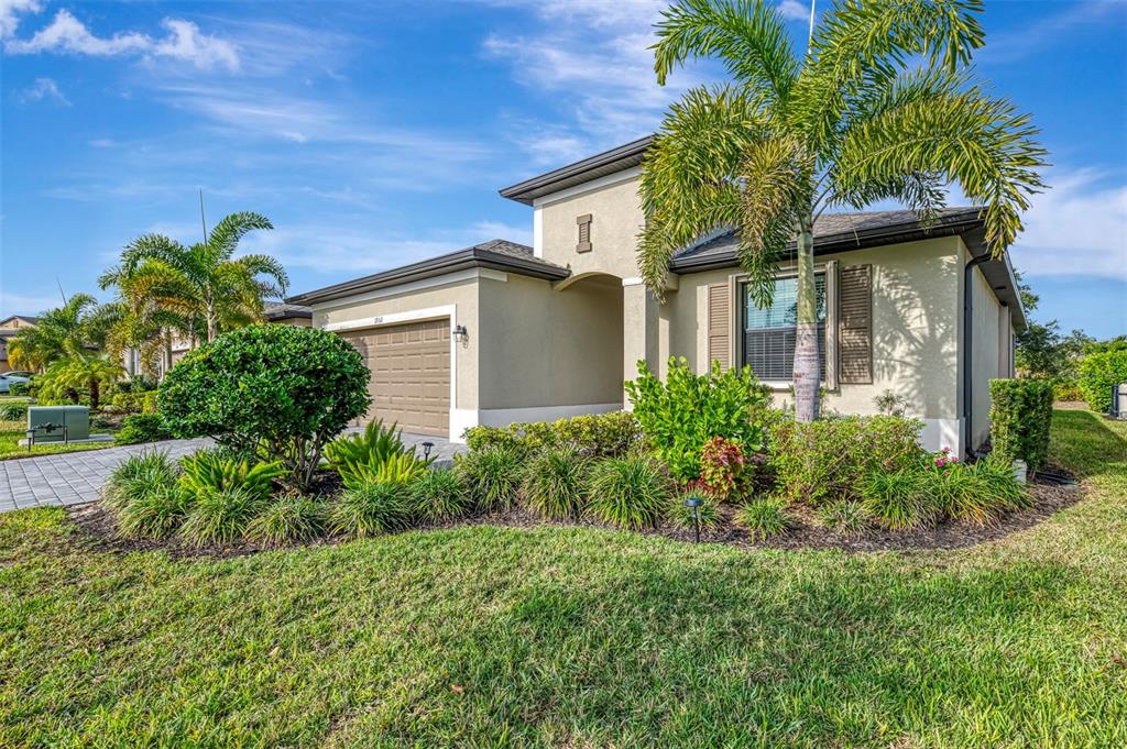 A single-story house with a tan stucco exterior, a two-car garage, and a palm tree — 1932 W ISLES ROAD, PORT CHARLOTTE, FL