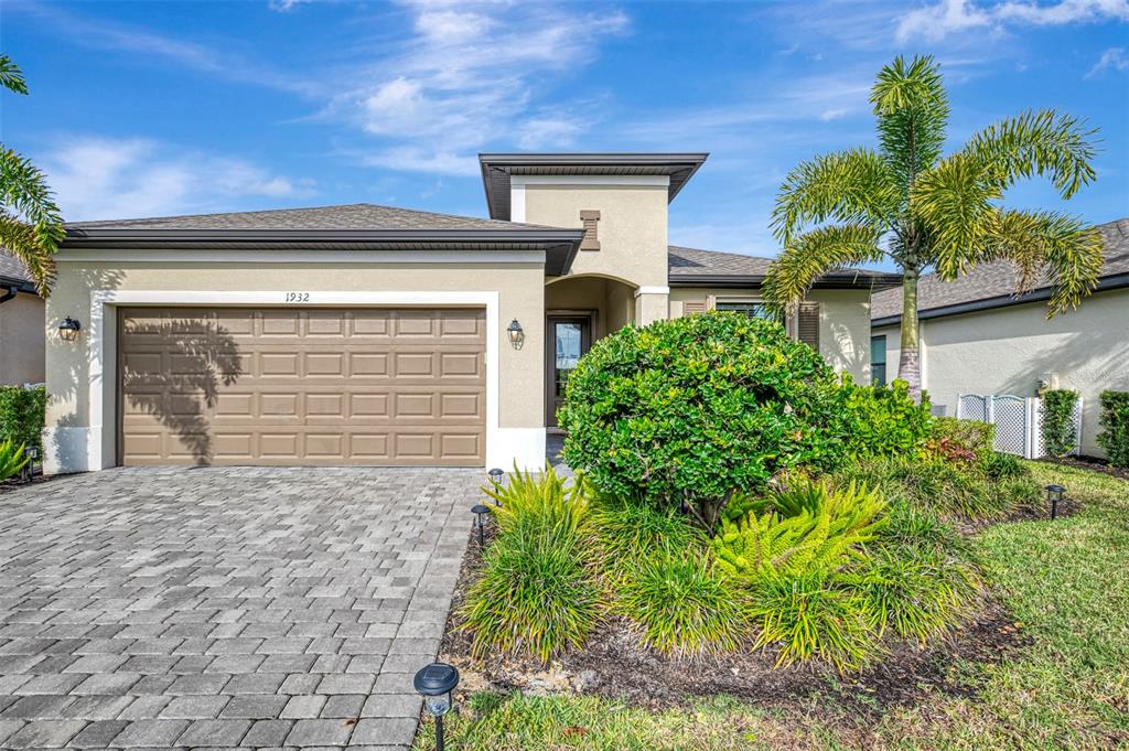A single-story house with a paved driveway, a two-car garage, and a palm tree — 1932 W ISLES ROAD, PORT CHARLOTTE, FL
