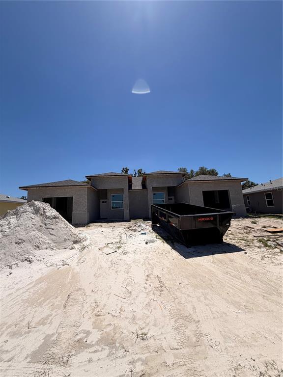 An exterior view of a new construction duplex with a large dumpster in the yard — 9305 ANITA AVENUE, ENGLEWOOD, FL