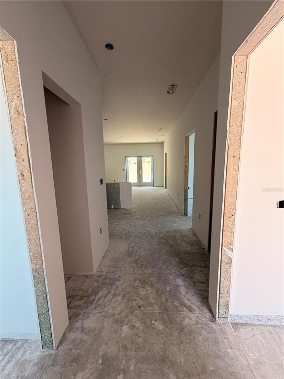 An unfinished interior hallway leads toward a room with glass doors and concrete flooring — 9305 ANITA AVENUE, ENGLEWOOD, FL