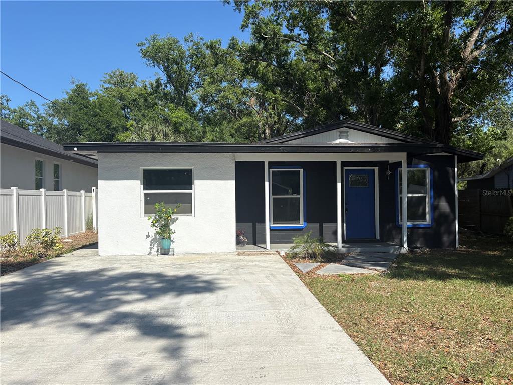 A single-story house with a white stucco section, dark siding, and a blue front door — 7019 N WILLOW AVENUE, TAMPA, FL