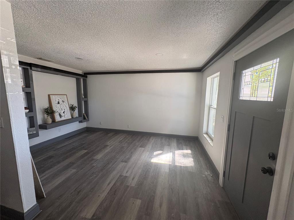 A room with gray wood-look flooring, white walls, dark trim, and built-in shelving — 7019 N WILLOW AVENUE, TAMPA, FL