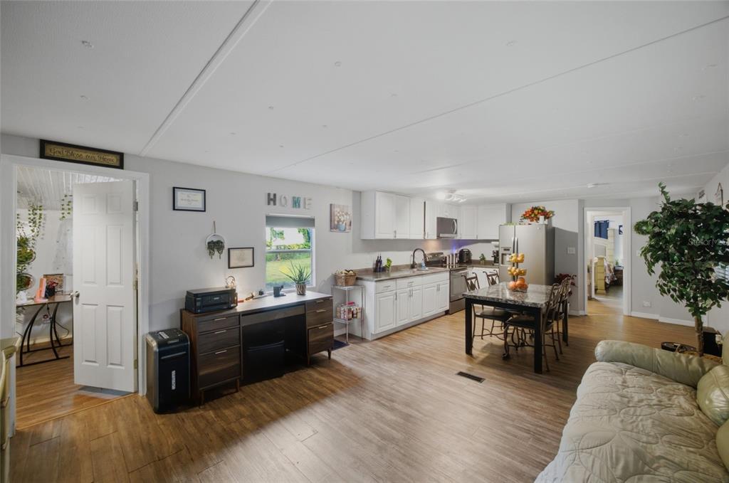 An open-concept kitchen and living area features white cabinets, a dining table, and wood flooring — 9605 ANDY DRIVE, HUDSON, FL