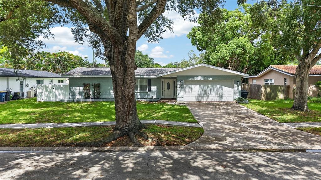 A single-story house with a light-colored brick exterior, a two-car garage, and large shade trees — 700 RUSKIN ROAD, CLEARWATER, FL
