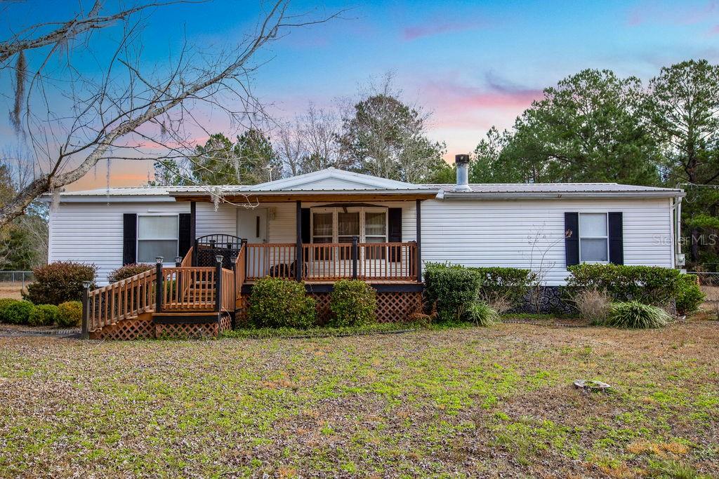 A single-story white manufactured home features a front porch with wooden railings and stairs — 2774 140TH TERRACE, LAKE CITY, FL
