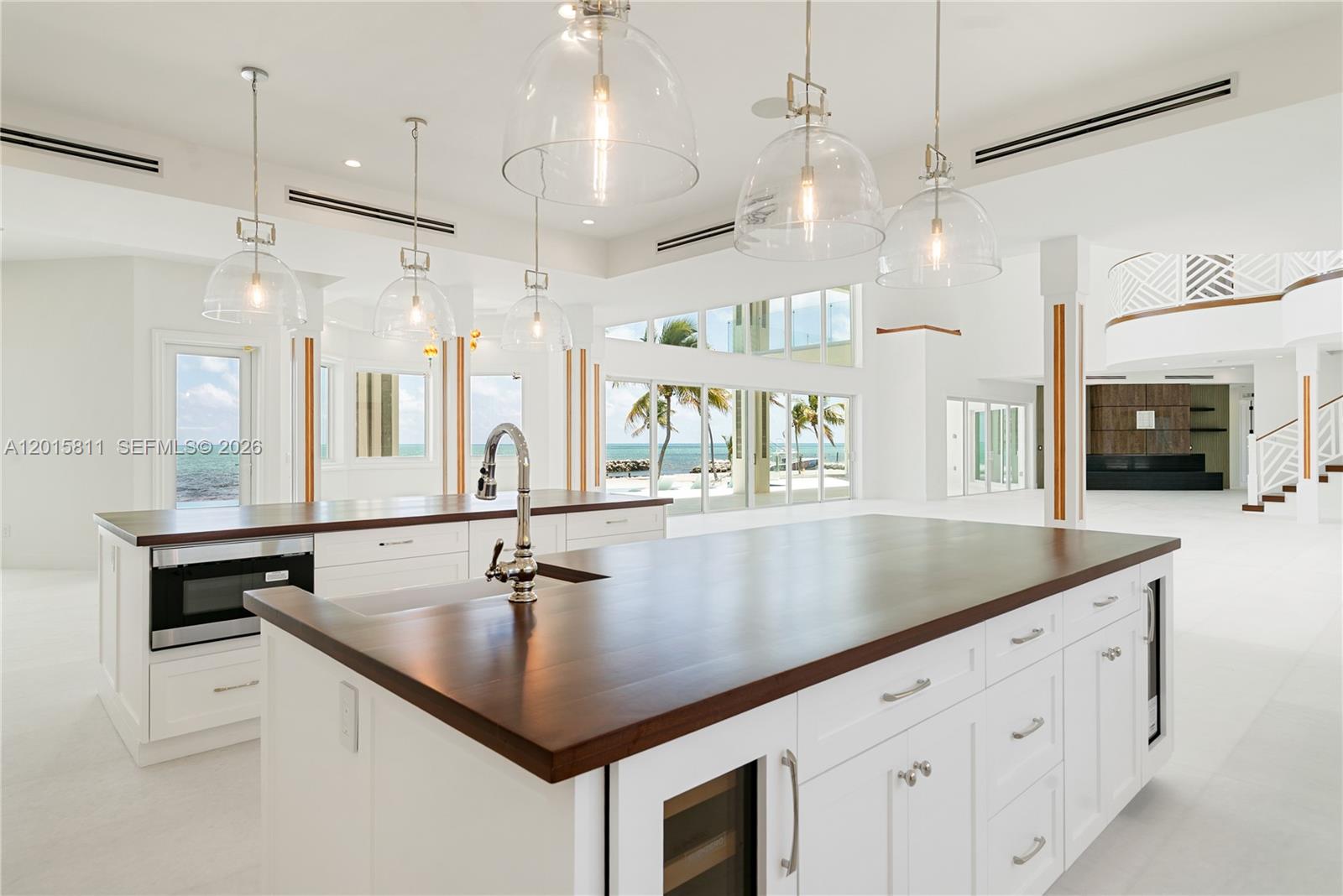 A bright kitchen features white cabinetry, dark wood countertops, and large glass pendant lights — 88835/88845 Old Hwy, Tavernier FL 33070, TAVERNIER, FL
