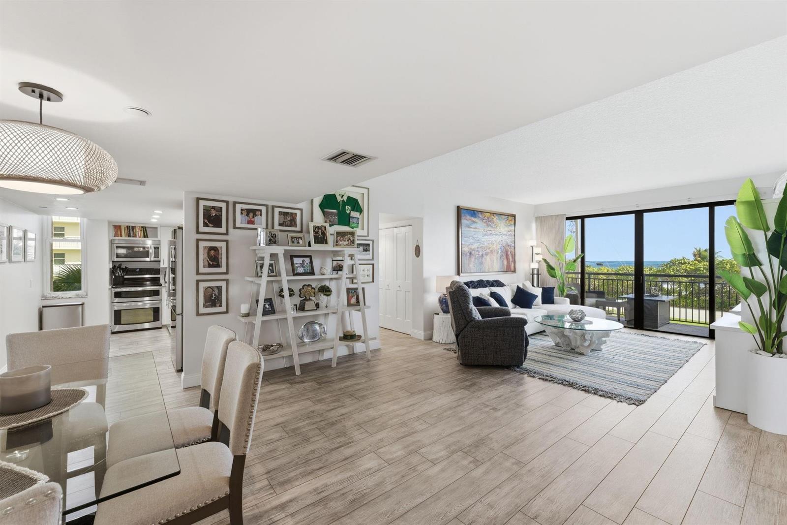 An open-concept living and dining area features light wood-look flooring and a balcony with ocean views — 2727 N Ocean Boulevard Unit 301, Boca Raton FL 33431, BOCA RATON, FL