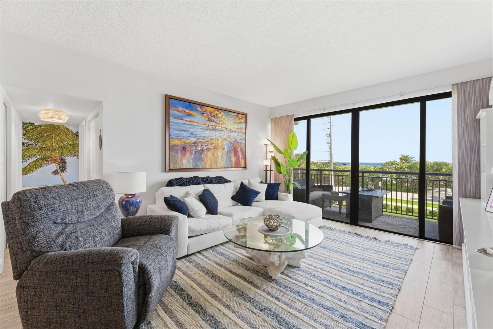 A living room features a white sectional sofa, a glass coffee table, and a balcony view — 2727 N Ocean Boulevard Unit 301, Boca Raton FL 33431, BOCA RATON, FL
