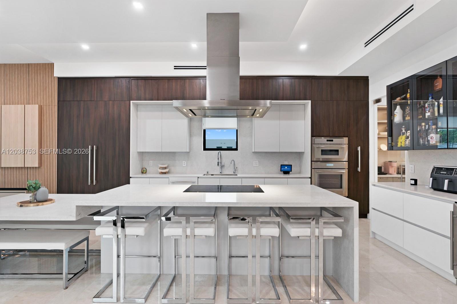 A modern kitchen features a large white island, dark wood cabinetry, and stainless steel appliances — 80 NW 129th Ave, Miami FL 33182, MIAMI, FL