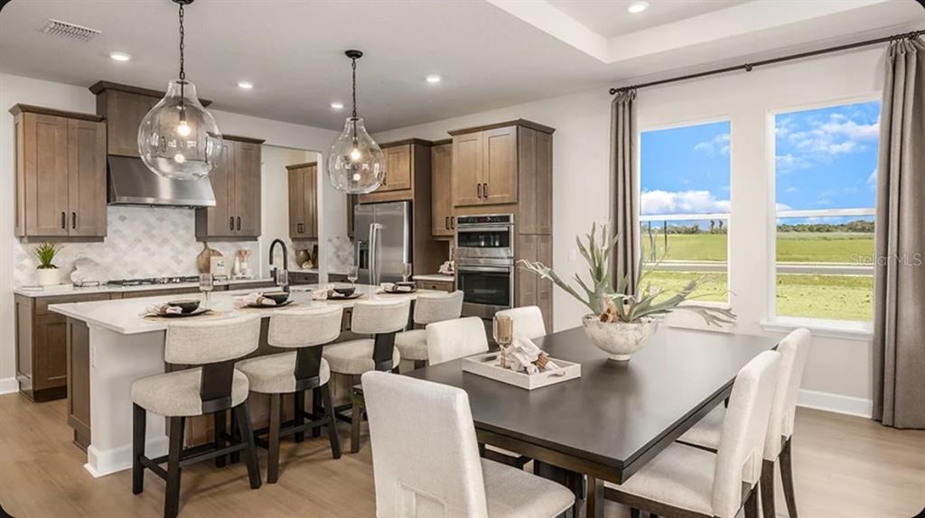 A kitchen and dining area with wood cabinets, a large island, and two glass pendants — 11783 RALLY RANGE WAY, SAN ANTONIO, FL
