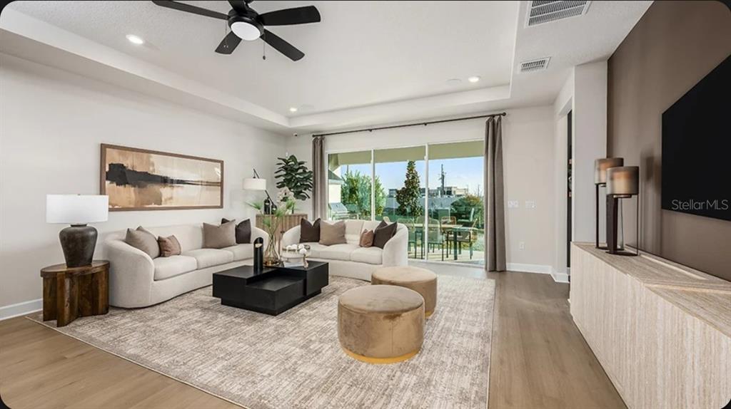 A living room with two beige sofas, a coffee table, and a large sliding glass door — 11783 RALLY RANGE WAY, SAN ANTONIO, FL