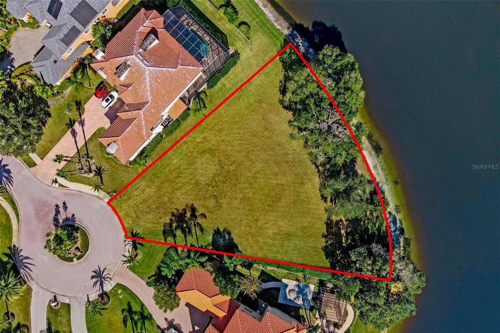 An aerial view shows a vacant waterfront lot outlined in red between two large houses — 17903 BIMINI ISLE COURT, TAMPA, FL