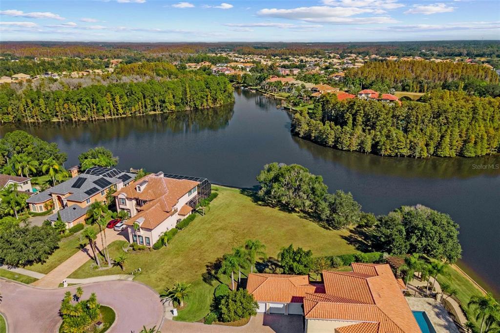 An aerial view shows a vacant, triangular waterfront lot outlined in red between two houses — 17903 BIMINI ISLE COURT, TAMPA, FL