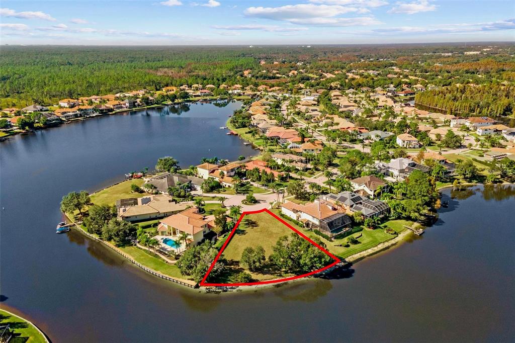An aerial view shows two large houses with terracotta roofs situated beside a winding lake — 17903 BIMINI ISLE COURT, TAMPA, FL