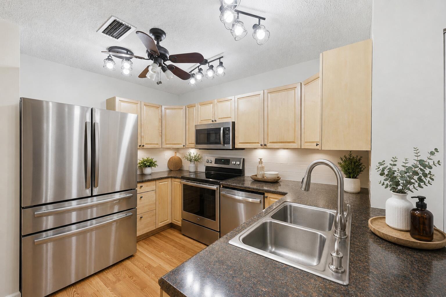 A kitchen features light wood cabinets, stainless steel appliances, and dark countertops — 600 Crosswinds # E1, FL 33413, FL