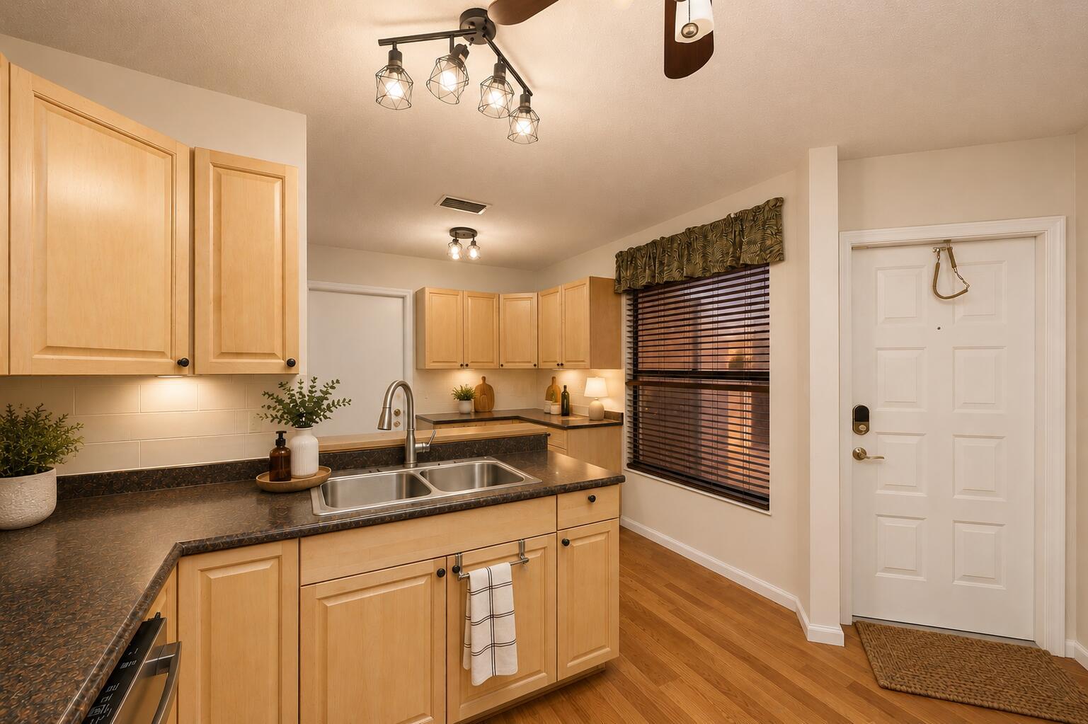 A kitchen features light wood cabinets, dark countertops, a double sink, and hardwood flooring — 600 Crosswinds # E1, FL 33413, FL