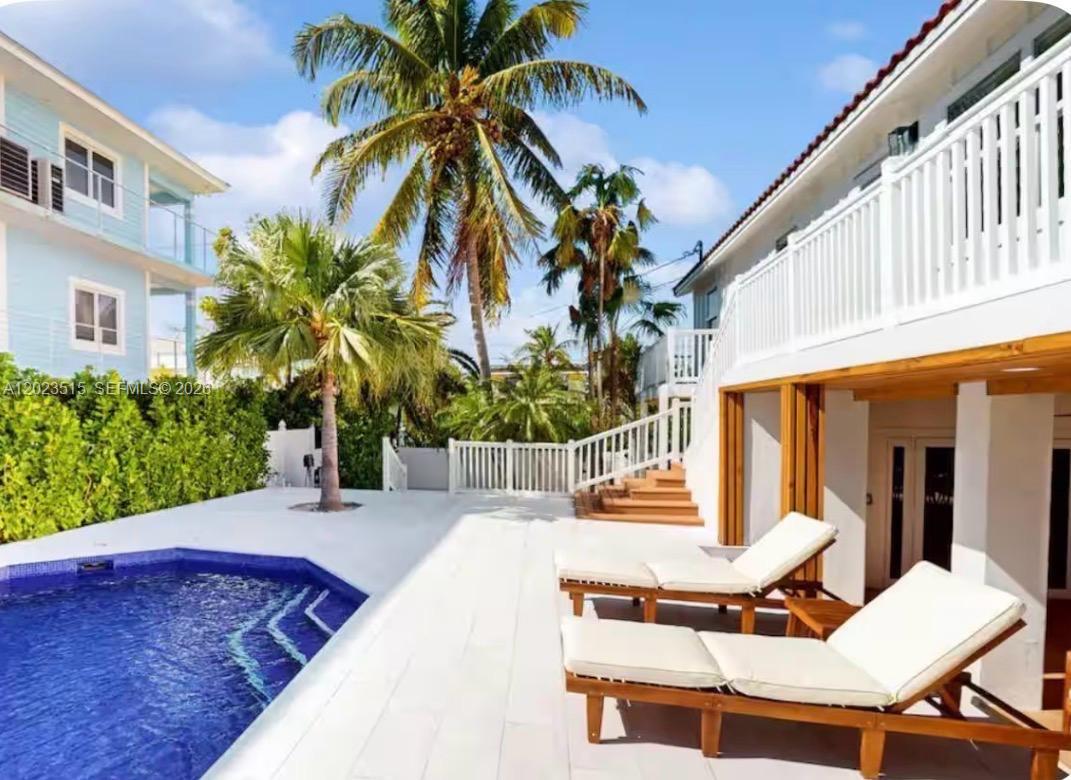 A swimming pool sits on a white patio next to two lounge chairs and buildings — 128 La Paloma Rd, Key Largo FL 33037, KEY LARGO, FL