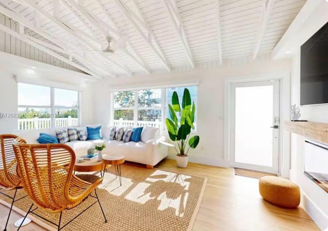 A bright living room features white vaulted ceilings, a sectional sofa, and a woven rug — 128 La Paloma Rd, Key Largo FL 33037, KEY LARGO, FL