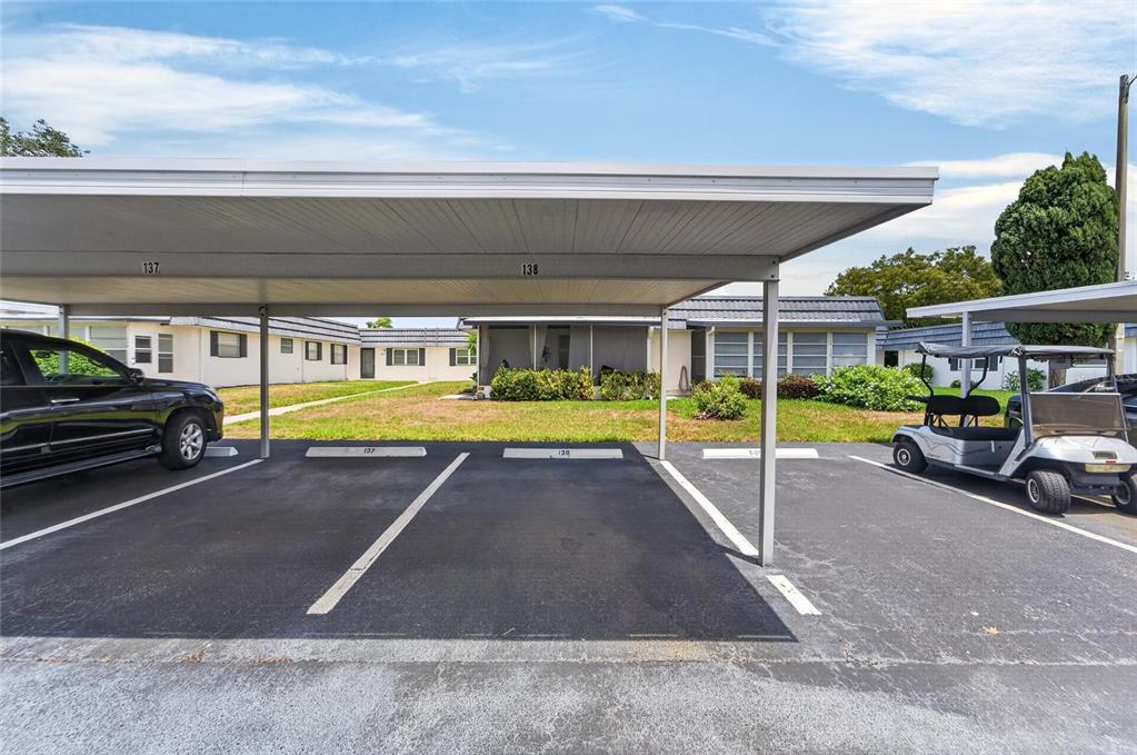 A covered parking area with numbered spaces sits in front of a residential building — 301 KINGS BOULEVARD UNIT 138, SUN CITY CENTER, FL