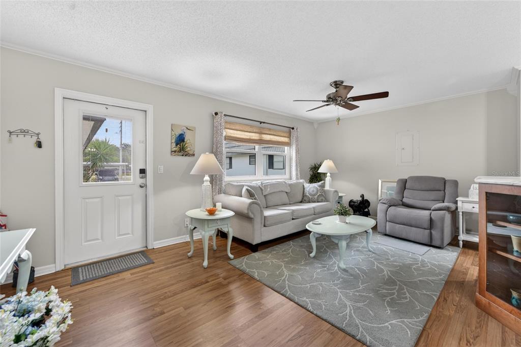 A living room features light-colored walls, wood flooring, a sofa, a recliner, and a rug — 301 KINGS BOULEVARD UNIT 138, SUN CITY CENTER, FL