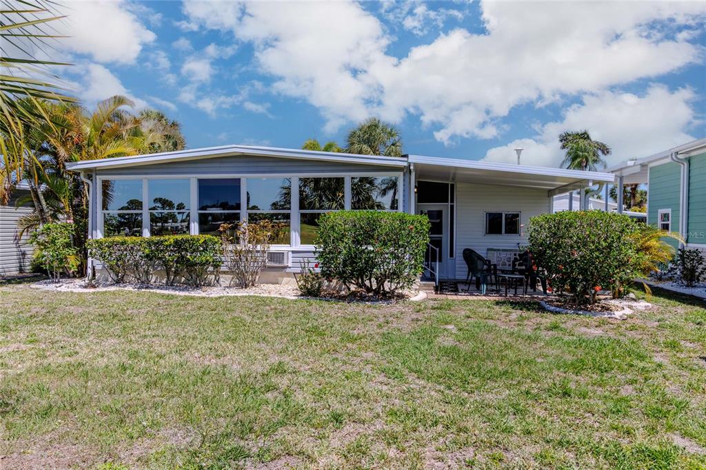 A single-story mobile home features a large sunroom with many windows and a covered patio — 2100 KINGS HIGHWAY UNIT 497, PORT CHARLOTTE, FL