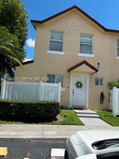 A two-story tan townhouse with a white front door and a white privacy fence — MARGATE, FL