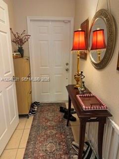 A narrow entryway features a patterned runner rug, a console table with a lamp, and a mirror — MARGATE, FL