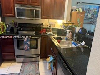 A kitchen features dark wood cabinets, stainless steel appliances, and black granite countertops — MARGATE, FL