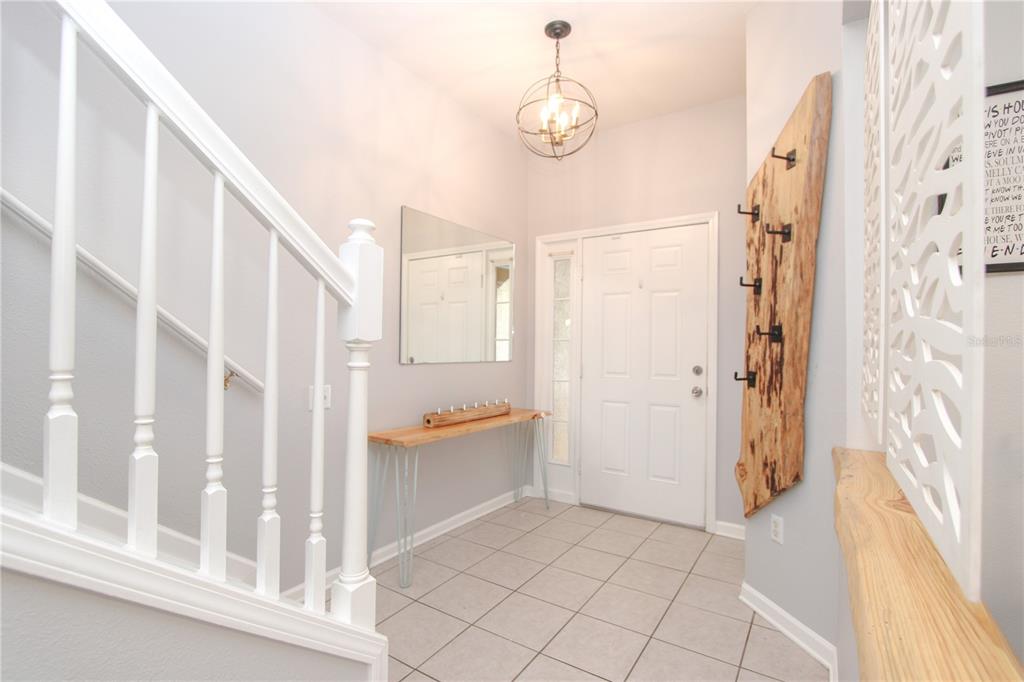A bright entryway features a white staircase, a wood console table, and a rustic coat rack — 2722 CONCH HOLLOW DRIVE, BRANDON, FL