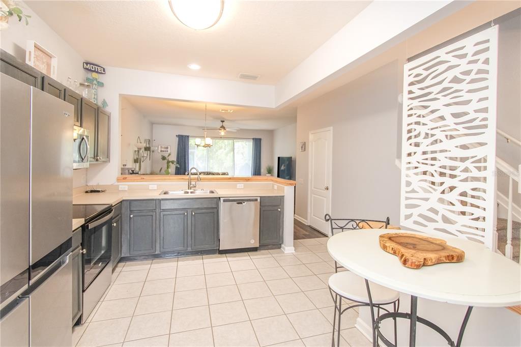 A kitchen with dark gray cabinets, stainless steel appliances, and a white breakfast table — 2722 CONCH HOLLOW DRIVE, BRANDON, FL