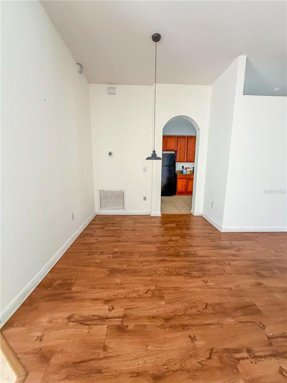 An empty dining area features wood-look flooring, a single pendant light, and an arched doorway — 3229 DUNSTABLE DRIVE, LAND O LAKES, FL