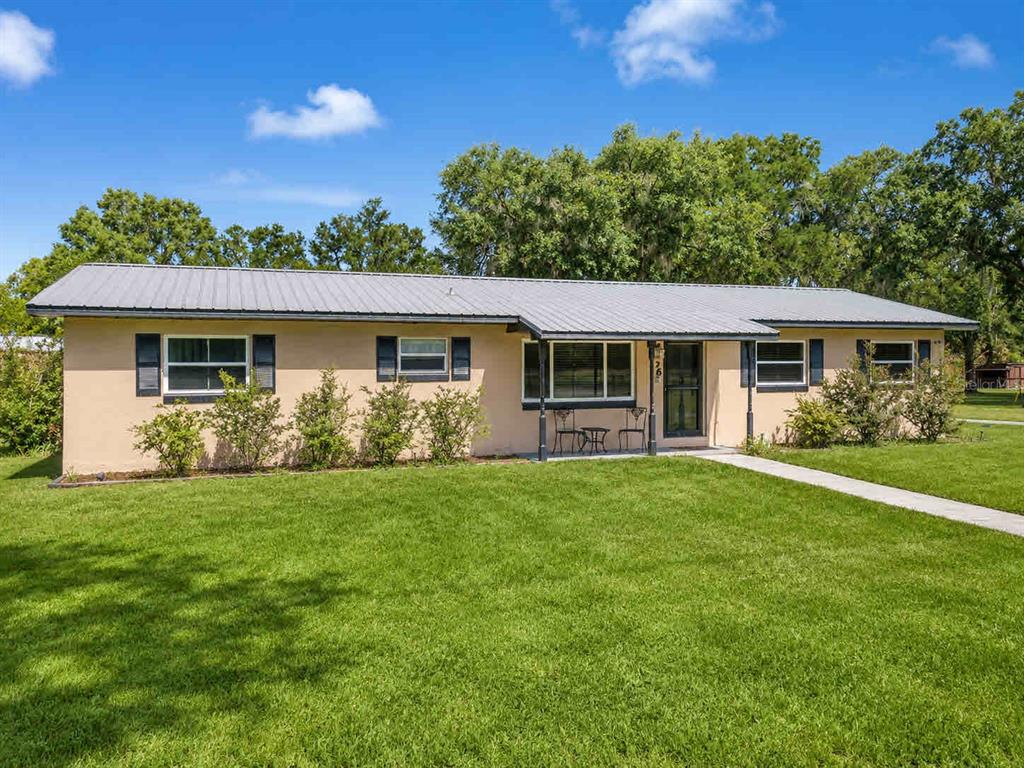 A single-story house with a metal roof, tan stucco exterior, and a front lawn — 196 NW 100TH AVENUE, OCALA, FL