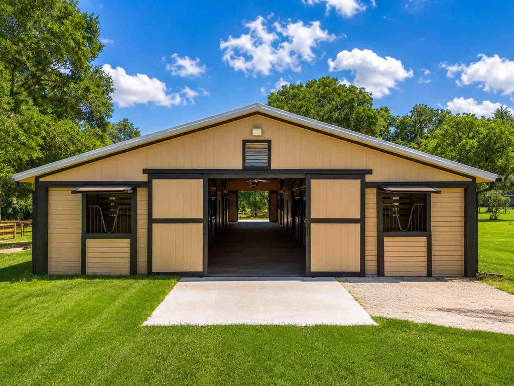 A tan barn with black trim and sliding doors sits on a grassy lot — 196 NW 100TH AVENUE, OCALA, FL