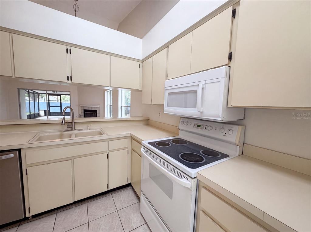 A kitchen features beige cabinets, a white electric range, and a double-basin sink — 8613 COTTONWAY LANE, TAMPA, FL