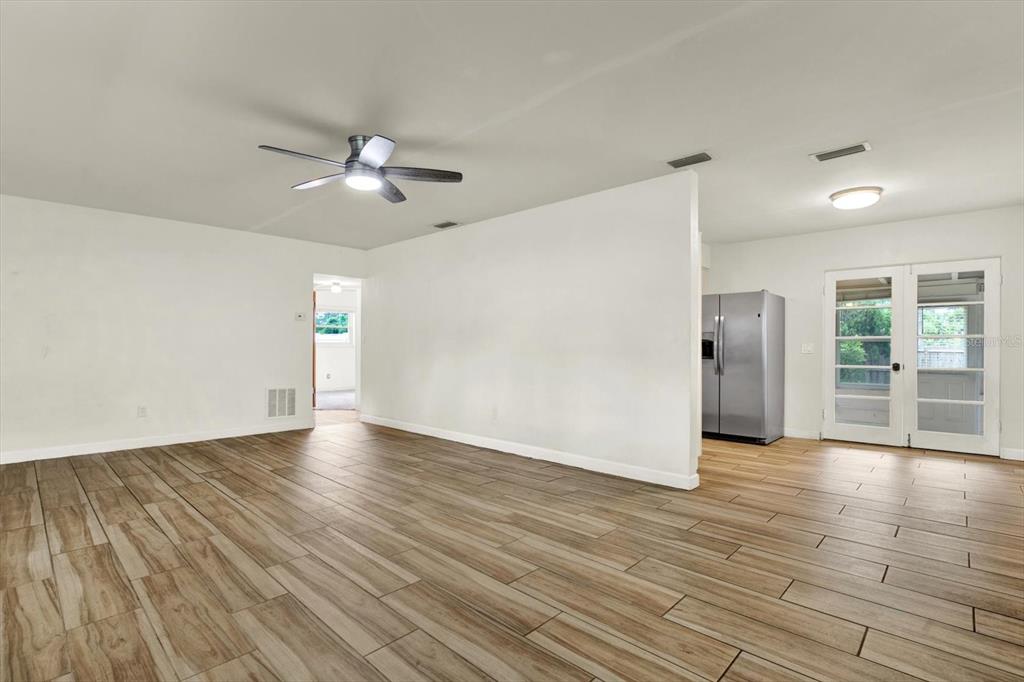 An open-concept living area with wood-look tile flooring, a ceiling fan, and a kitchen view — 8567 RIDGE ROAD, SEMINOLE, FL