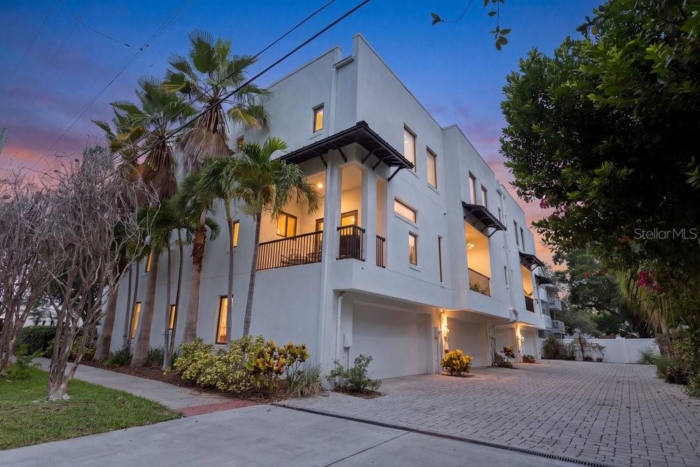 A modern white multi-story townhouse with a paved driveway, balconies, and palm trees at dusk — 514 S GLEN AVENUE, TAMPA, FL