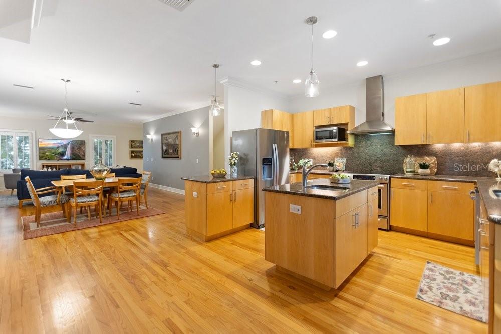 A kitchen with light wood cabinets and a center island opens to a dining area — 514 S GLEN AVENUE, TAMPA, FL