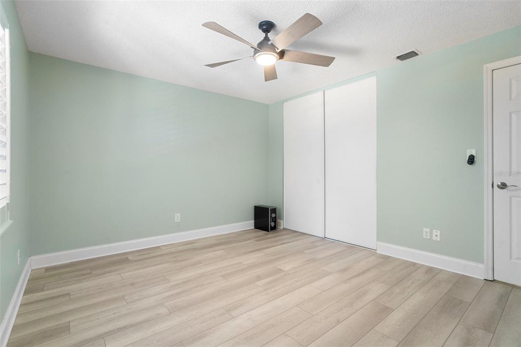 An empty bedroom features light green walls, wood-look flooring, a ceiling fan, and sliding closet doors — 5 ESCONDIDO CIRCLE UNIT 46, ALTAMONTE SPRINGS, FL