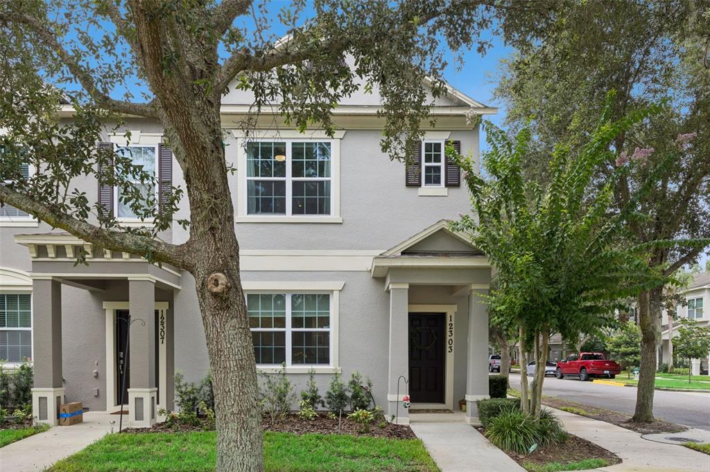 A two-story gray townhouse with a covered front entrance and a large tree in front — 12303 LANGSTAFF DRIVE, WINDERMERE, FL