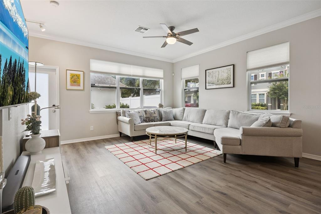A living room features a light gray sectional sofa, a round coffee table, and wood flooring — 12303 LANGSTAFF DRIVE, WINDERMERE, FL