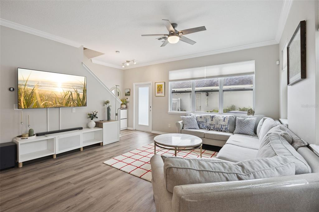 A living room features a sectional sofa, a wall-mounted television, and wood-look flooring — 12303 LANGSTAFF DRIVE, WINDERMERE, FL