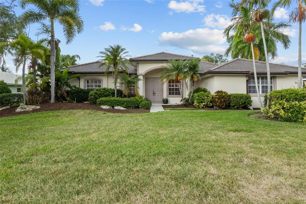 A single-story house with a tiled roof, palm trees, and a landscaped front yard — 8315 DEERBROOK CIRCLE, SARASOTA, FL