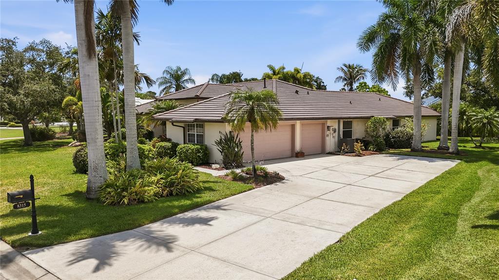 A single-story house with a brown tile roof, two-car garage, and palm trees in front — 8315 DEERBROOK CIRCLE, SARASOTA, FL