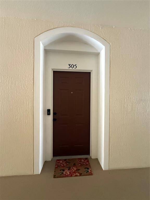 A brown apartment door labeled 305 is set within an arched entryway — 6214 STEVENSON DRIVE UNIT 305, ORLANDO, FL