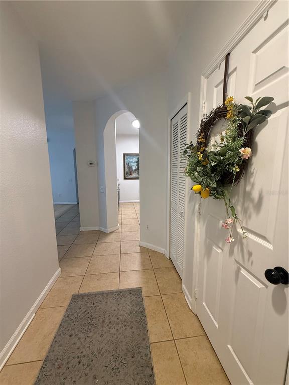 A tiled hallway features a white door with a wreath and an arched entryway beyond — 6214 STEVENSON DRIVE UNIT 305, ORLANDO, FL