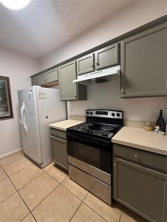 A kitchen features olive green cabinets, a white refrigerator, and a stainless steel electric stove — 6214 STEVENSON DRIVE UNIT 305, ORLANDO, FL
