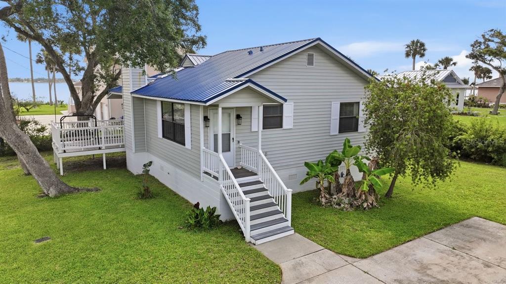 A light gray house with a blue metal roof sits on a grassy lot — 105 MCDONALD STREET, SOUTH DAYTONA, FL