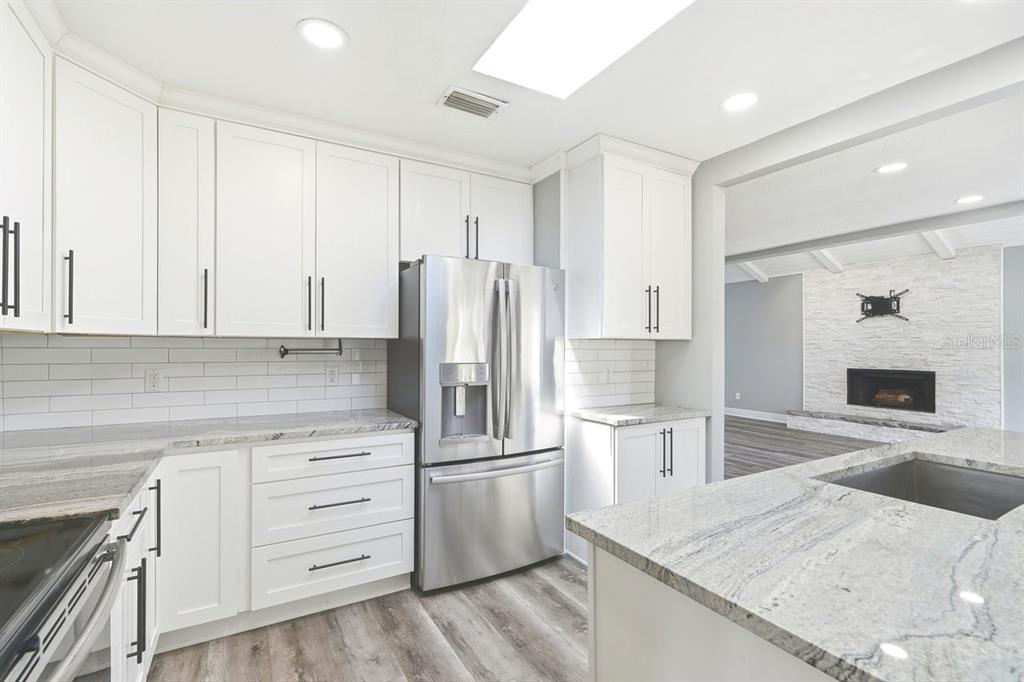 A modern kitchen features white cabinets, stainless steel appliances, and granite countertops — 105 MCDONALD STREET, SOUTH DAYTONA, FL
